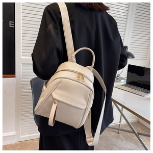 Detail of cream white leather backpack with litchi texture and gold hardware on a model