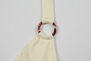 Detail of cream knit dress featuring amber resin ring connector and pleated straps