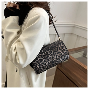 Fashionable leopard print shoulder bag worn over the shoulder by a model in a white coat