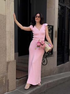 Pink knit two-piece set featuring a V-neck button vest and matching long skirt outdoors