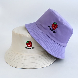 Detailed strawberry embroidery on cream and lilac bucket hats with soft fabric texture