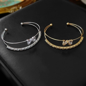 Elegant gold and silver bow open bangles with zircon accents on a black background