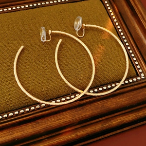 Dettaglio di orecchini a clip in oro opaco con cuscinetti in silicone in cornice vintage
