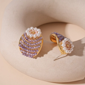 Macro shot of vintage flower earrings with purple beads and white pearls on golden base