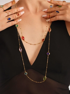Detail der bunten Kristallhalskette und goldener Ringe mit facettierten Steinen