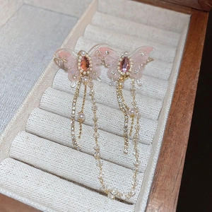 Detail of pink butterfly earrings featuring zircon accents and long chain tassels