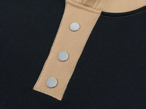 Detail of black and khaki knit fabric with three silver metal buttons on the placket