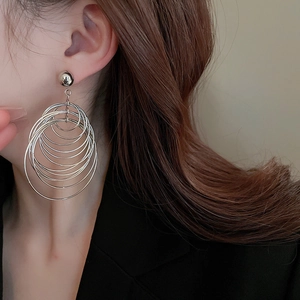 Close-up of oversized multi-layered silver hoop earrings with spherical stud on model