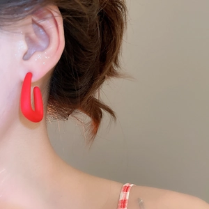 Detail view of a red matte geometric C-shaped earring on a model with elegant styling