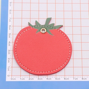 Detail view of red tomato leather keychain showing 6.5cm diameter on measuring mat