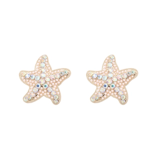 Vue macro de boucles d'oreilles étoile de mer dorées avec perles et strass AB colorés