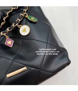 Detail of quilted leather bag with gold chain and colorful heart-shaped charms