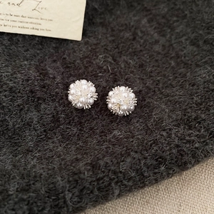 Detailed macro of clustered pearl flower studs on grey knit fabric with a vintage card