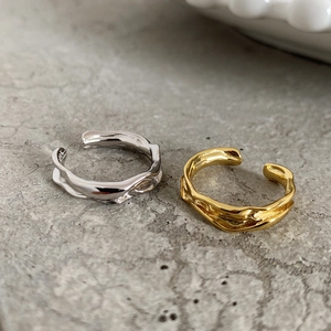Detailed macro view of irregular lava texture on adjustable gold and silver open rings