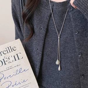 Detail of Y-shaped silver chain necklace with marble drop pendant on a model