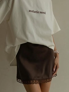 Detailed view of dark brown satin midi skirt featuring delicate floral lace trim at the hem