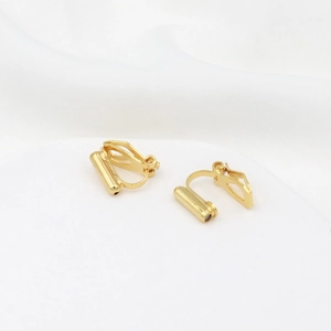 Macro shot of gold-plated 18K converters for non-pierced ears on white fabric