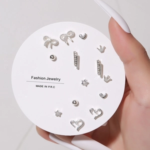 Close-up of silver stud earring set featuring bow, heart, and star designs on jewelry card