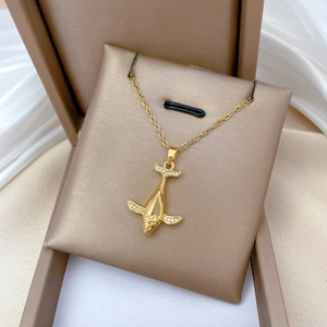 Macro detail of gold whale pendant with clear crystals on luxury beige display