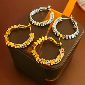 Detailed macro view of gold and silver plated hoop earrings with cubic zirconia on a box