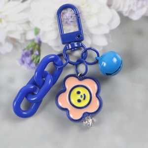 Close-up of blue plastic chain keychain with a yellow smiley face flower and bell charm
