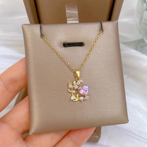 Detail of leaf-shaped heart pendant with pink stone and zircon inlay on gold chain