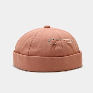 Detailed close-up of a cotton docker hat in terracotta with a silver metal pin accessory