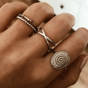 Close-up of four stacked S925 sterling silver rings with cross and bead designs on fingers
