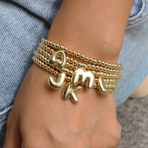 Detail of 18k gold plated 3D alphabet charms on stretch bead bracelets worn on wrist