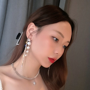Elegant long tassel earrings with faux pearls and stars worn by a model in soft lighting