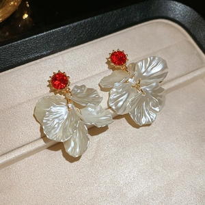 Detail view of pearl petal earrings with red gemstones and gold plating on jewelry display