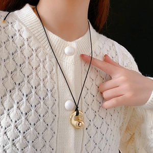 Detailed view of geometric irregular pendant on black cord worn by a model