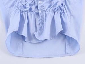 Detailed close-up of light blue poplin shirt featuring ruffled hem and white buttons