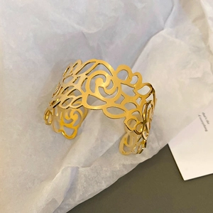 Close-up of golden hollow cuff bracelet with intricate floral cut-out patterns