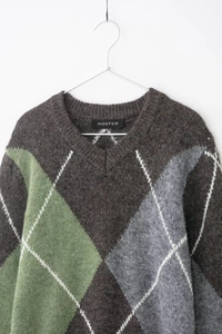 Détail d'un pull en maille à col en V avec motifs à losanges marron, vert et gris