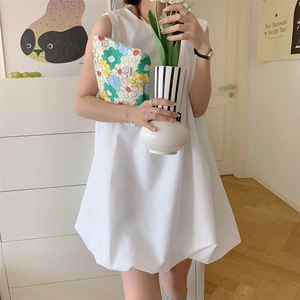 Close-up of floral cotton pouch held by a model in a minimalist white dress