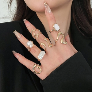 Close-up of elegant gold stackable rings with pearls worn on model's hand with suit