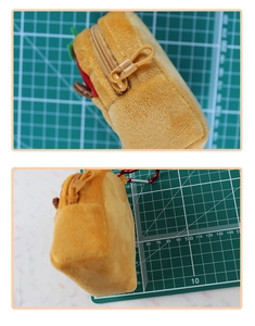 Detail view of plush Capybara coin purse with red hook and side zipper texture
