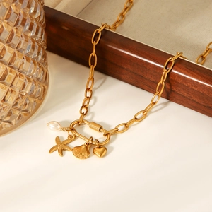 Collar dorado con dijes de estrella de mar perla corazón en bandeja de madera y cristal