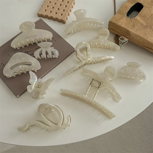 Set di mollette per capelli in acetato color crema in vari stili su un tavolo bianco