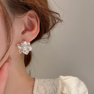 Detail of elegant gold-edged flower earring with a pearl center worn by a model
