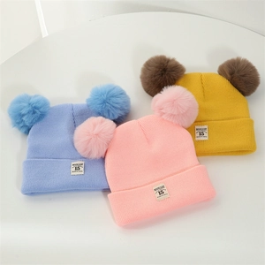 Close-up of baby winter knit hats in pink, blue and yellow with double soft pom-poms