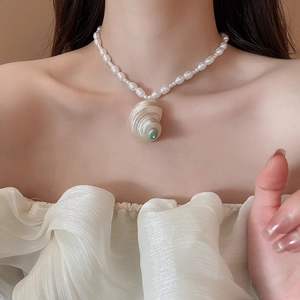 Detail of irregular shell conch pendant on elegant pearl beaded necklace for women