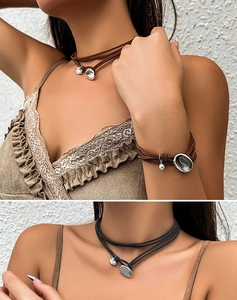 Detail of layered leather choker and bracelet set with silver oval pendants in brown and black