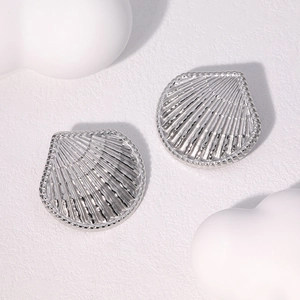 Detail view of silver fan-shaped stainless steel stud earrings on a minimalist background
