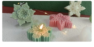 Detailed close-up of colorful snowflake-shaped scented candles on artificial snow