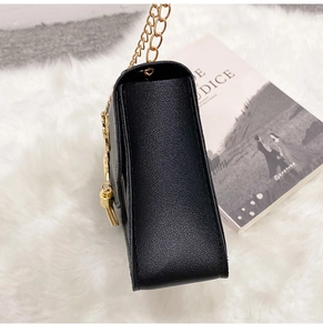 Side view of black lychee texture crossbody bag with gold chain and tassel detail