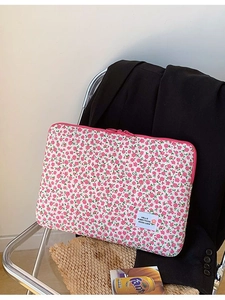 Pink floral laptop sleeve for 11-15 inch devices shown on a chair in a stylish setting