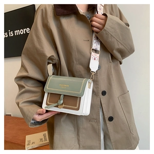 Detail of crossbody bag featuring green flap, brown pocket, and geometric wide strap