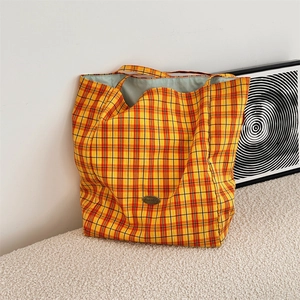 Macro detail of high-capacity checkered tote bag with Sozakka metal logo and woven texture